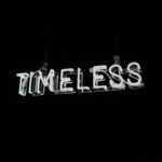White neon word timeless on black background