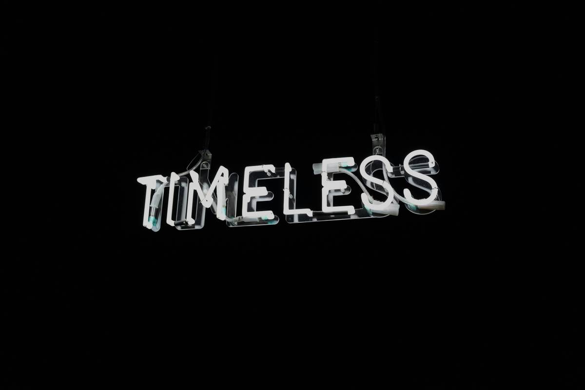 White neon word timeless on black background